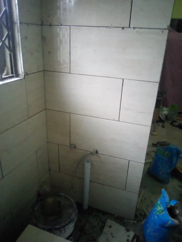 Completed bathroom wall tiling with plumbing rough-in visible
