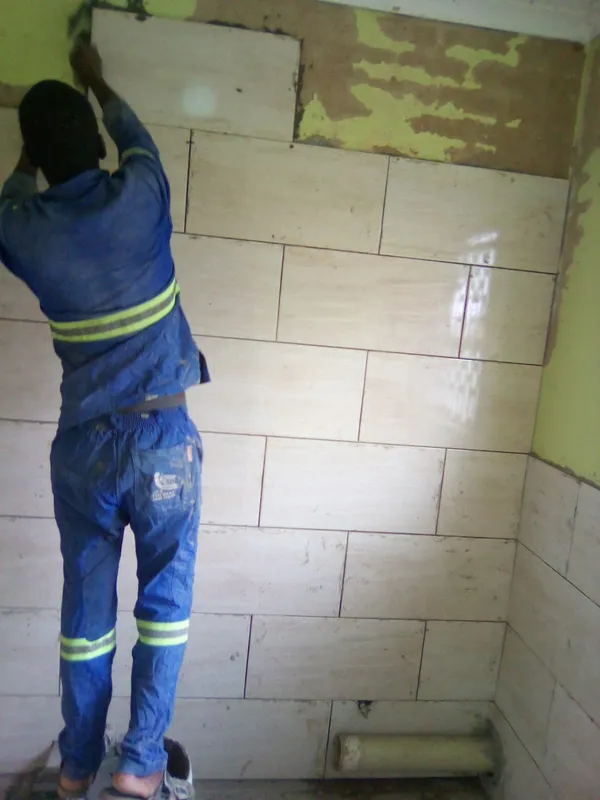 Technician installing large format wall tiles in a bathroom renovation